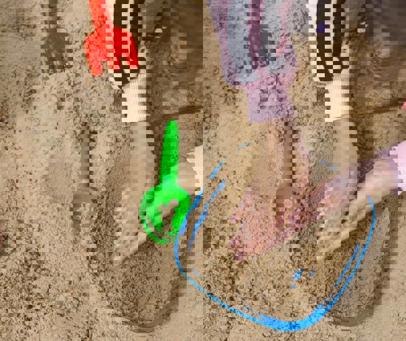 Young child's hands in sand