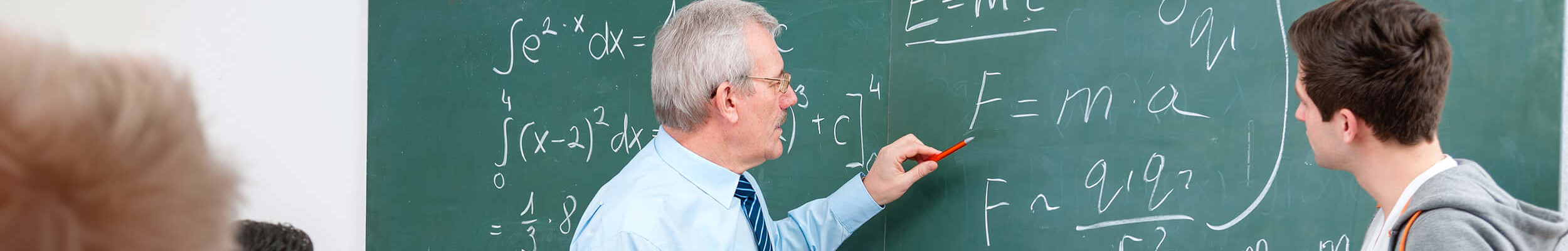 Teacher and student looking at maths equation on board