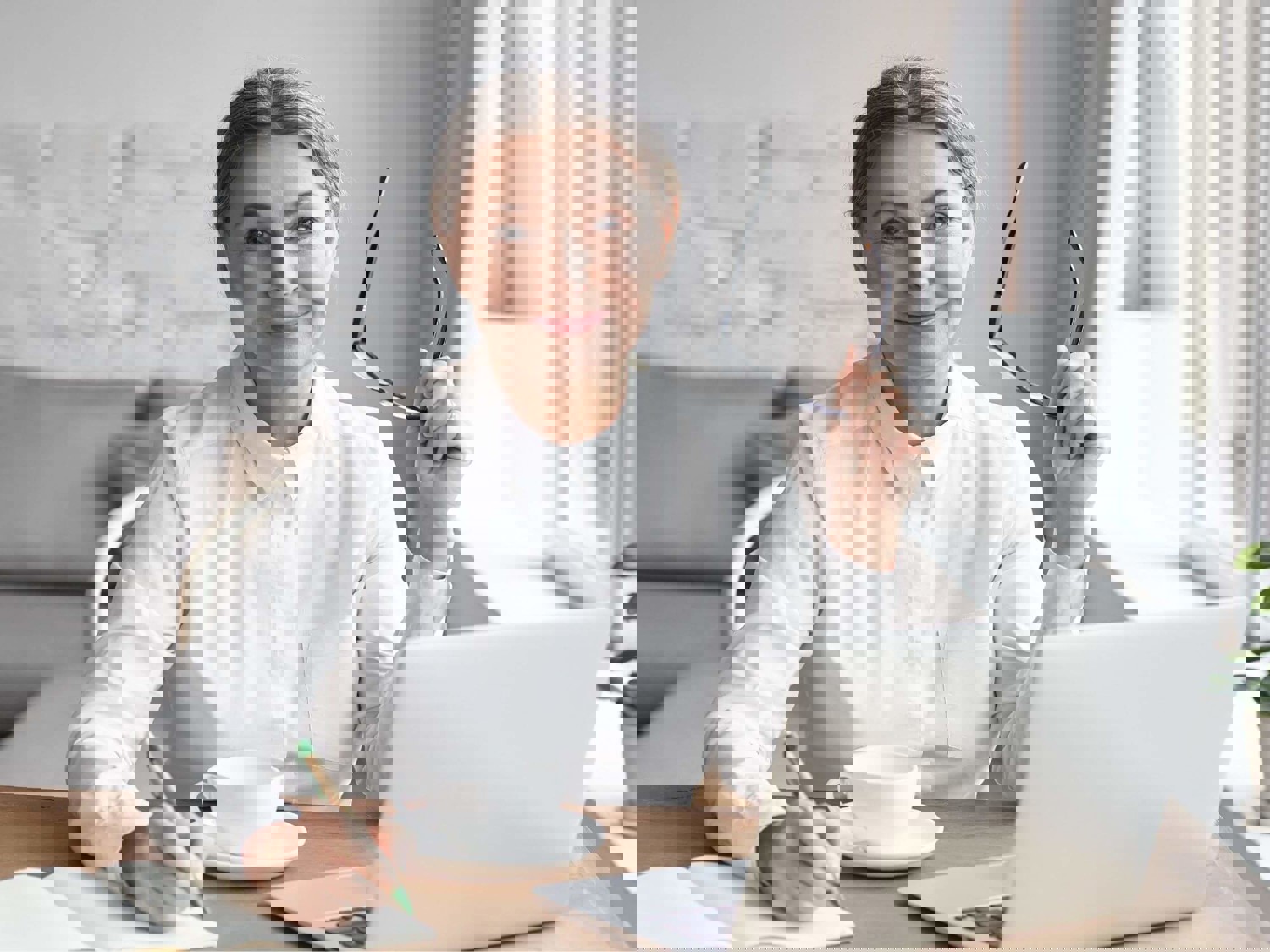 Lady writing in notebook at laptop