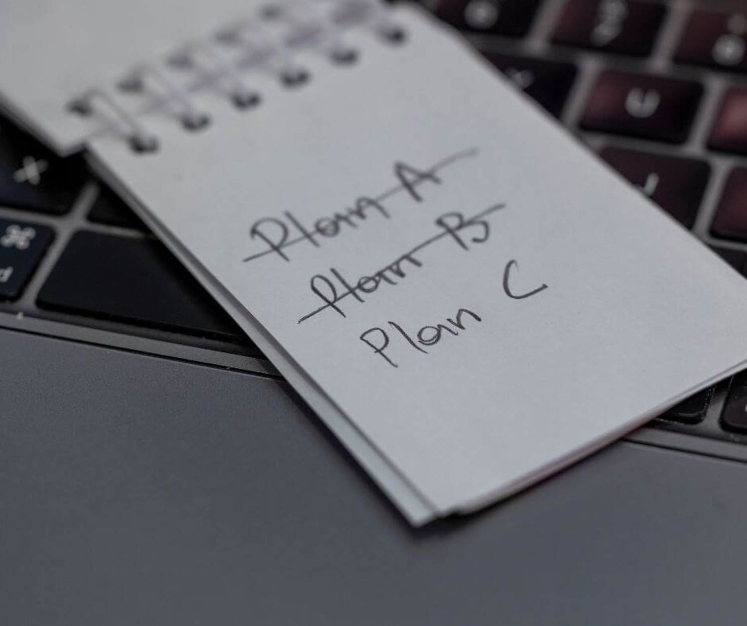 Always have a backup: Keyboard with a notepad laid on top with a Plan A, Plan B, Plan C note
