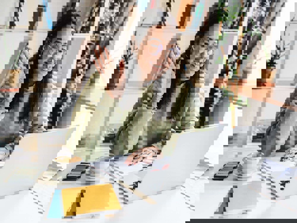 Woman smiling and waving at someone on laptop screen