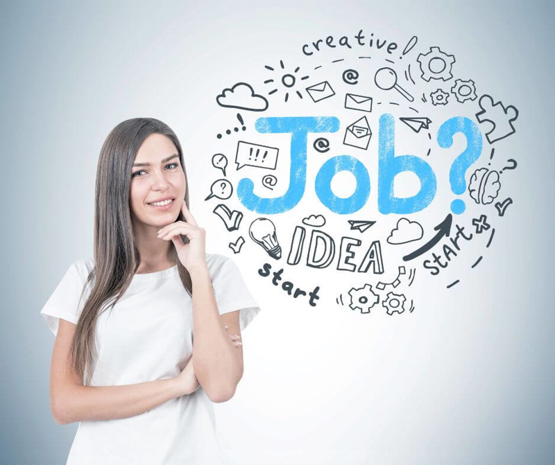 Smiling young woman with fair hair wearing a white T shirt and thinking while looking at the viewer. A grey wall with a round job search sketch on it.