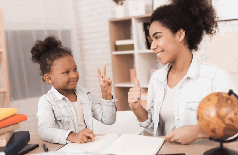 Young girl doing peace sign to woman with thumbs up