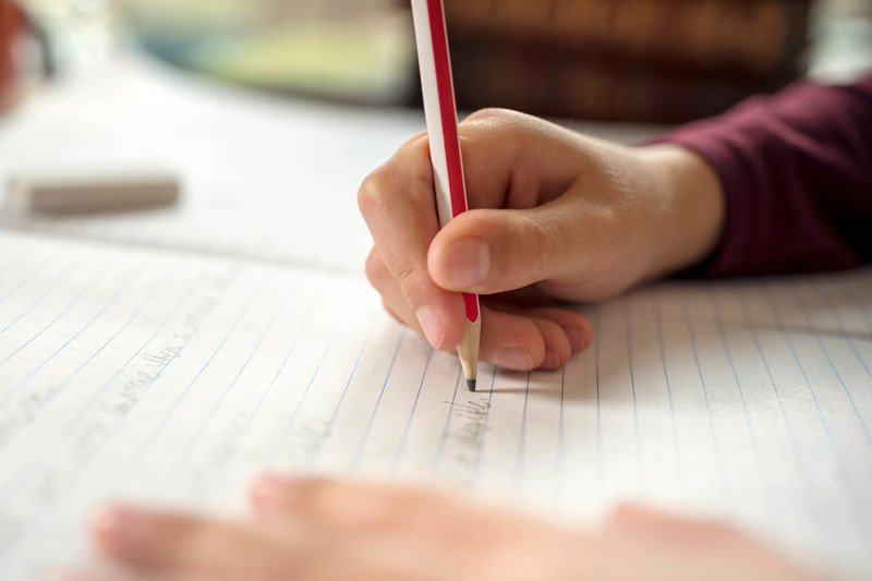 Writing on lined paper with a pencil