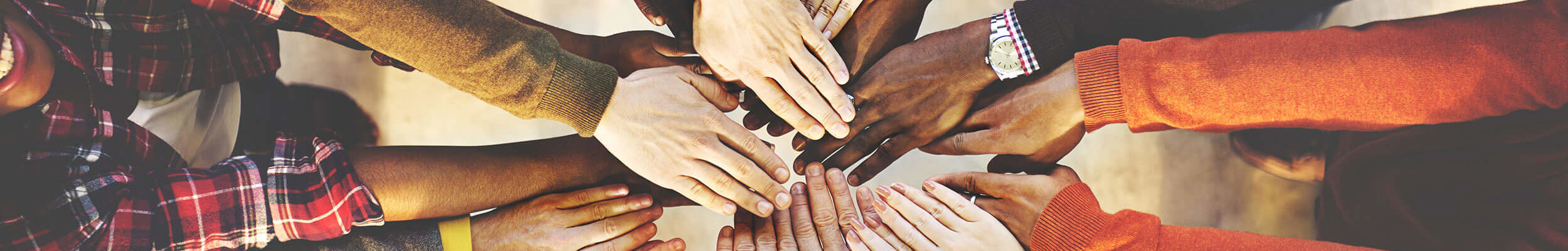 Group of people in a circle, with their hands held in the middle