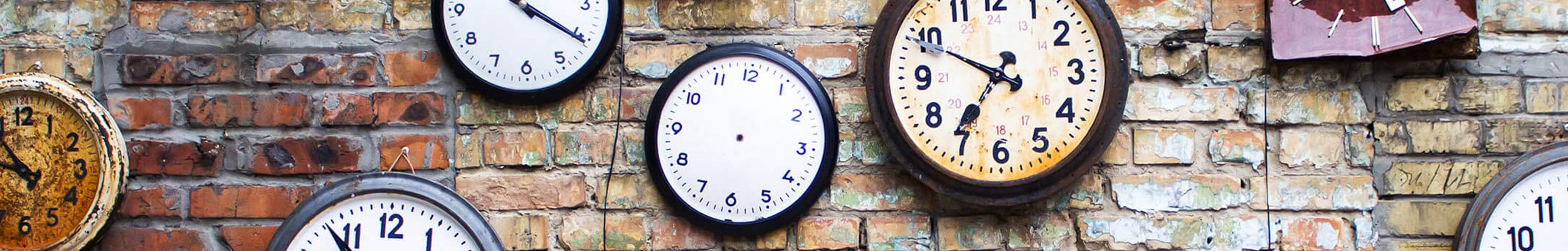 Lots of clocks on a brick wall