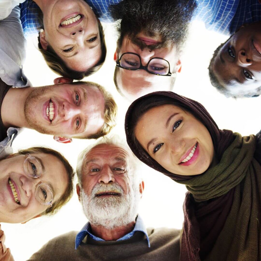 Group of people standing in a circle, looking down at the camera smiling